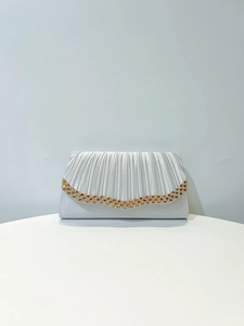Détail de pochette de soirée en satin argenté avec plis radiants et strass doré orangé