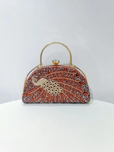 Detailed view of red and silver peacock rhinestone patterns on this clutch bag