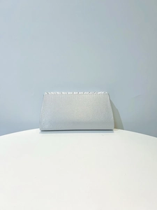 Détail d'une pochette de soirée en satin gris argenté avec plis élégants sur le dessus
