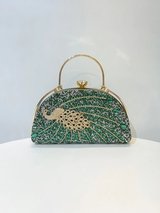 Detail of green crystal evening clutch bag featuring a golden peacock rhinestone ornament