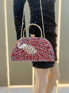 Detailed shot of peacock rhinestone evening bag with red crystals and gold handle