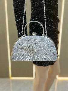 Close-up of silver rhinestone clutch bag with elegant peacock pattern and metal handle