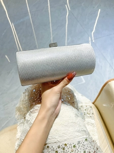Close-up of silver glitter evening clutch with crystal clasp held by model in white dress