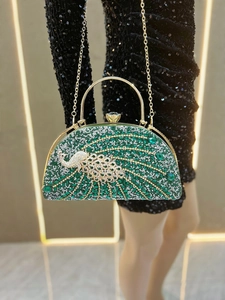 Detailed view of luxury peacock evening bag with green rhinestones and gold handle