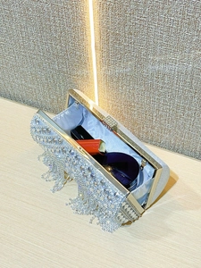 Macro detail of silver clutch bag interior showing lipstick space and fringe accents
