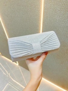 Detail of silver pleated clutch bag with bow design and shimmering sequins for parties