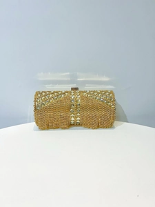 Detail of golden evening clutch bag featuring rhinestones, tassel fringe, and large gems
