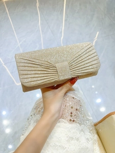 Close-up of golden sequined evening clutch featuring radial pleated design and shiny finish