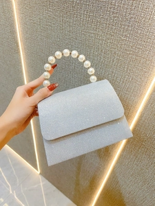 Close-up of silver glitter evening clutch bag featuring a luxurious pearl top handle