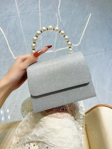 Detail of silver sequin evening bag featuring a luxury pearl handle with rhinestone accents