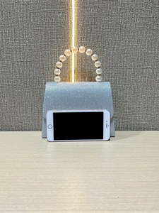 Detail view of sparkly evening bag with pearl handle and iPhone for size reference