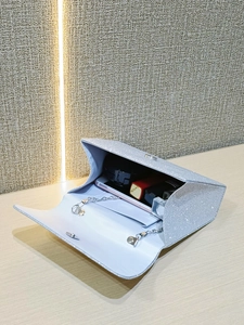 Detail view of silver sequin evening bag interior with phone and cosmetics inside