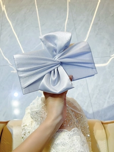 Detail view of a silver-blue satin evening clutch with a large decorative bow
