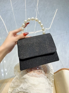 Detail of elegant black sequin evening bag featuring a premium white pearl handle