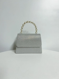 Detail of silver glitter evening bag featuring a distinctive large pearl bead handle