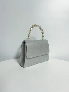 Detail of silver evening clutch with elegant pearl handle and sparkling glitter finish