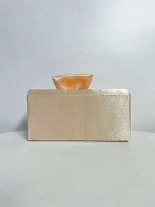 Detailed front view of a champagne gold satin evening clutch bag with elegant pleated bow