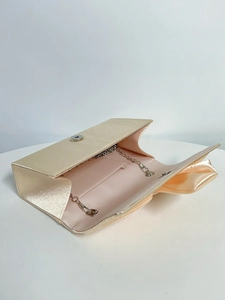 Detail of champagne satin evening clutch with bow, metal chain and silver magnetic clasp