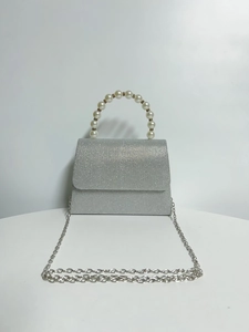 Detail of silver glitter evening bag with pearl handle and metal chain strap