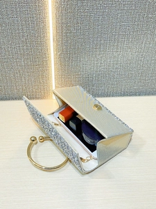 Detail view of silver glitter evening bag interior holding a phone and cosmetics