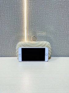 Detail of white pearl evening bag with wavy texture and sparkling rhinestone buckle