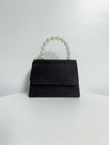Detail of black glitter evening clutch with white pearl beaded handle and flap closure