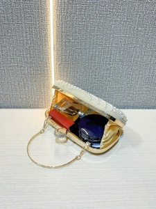 Top view of white pearl evening bag showing interior space and golden metal handle