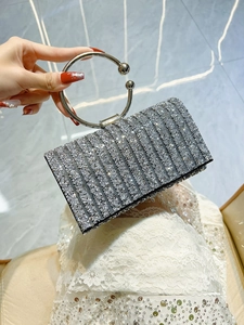 Close-up of elegant silver glitter clutch bag with metal ring handle and vertical textures