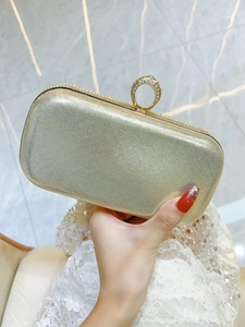 Detail of glitter gold evening clutch with a sparkling rhinestone ring buckle and lace dress
