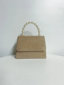 Detailed close-up of a gold sequin evening clutch bag with an elegant faux pearl handle