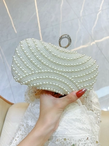 Detail of white pearl evening clutch with wavy pearl patterns and rhinestone ring clasp