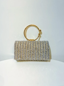 Detail of silver sparkling clutch bag featuring a distinctive golden circular ring handle