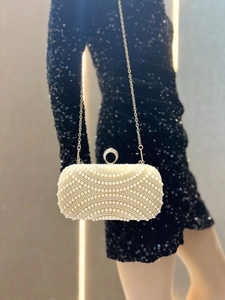 Close-up of luxury white pearl evening bag with sparkling diamond buckle and chain