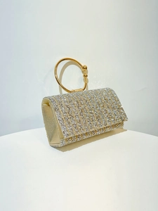 Detail of elegant gold evening clutch bag with sparkling rhinestones and metal ring handle