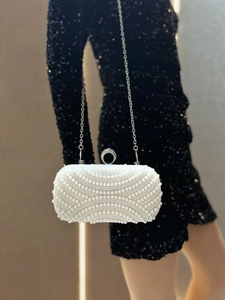 Close-up of luxury white pearl evening clutch with sparkling rhinestone buckle and silver chain