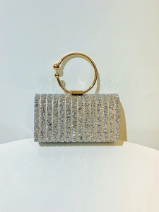Detail of elegant evening clutch with silver rhinestones and gold circular handle