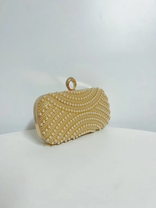 Detail of white pearl evening bag with wavy stitching and sparkling rhinestone ring clasp