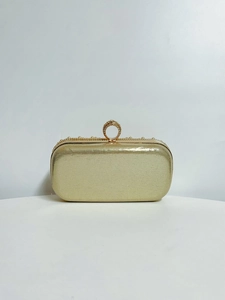Detail of gold evening clutch with pearl trim and rhinestone ring handle clasp