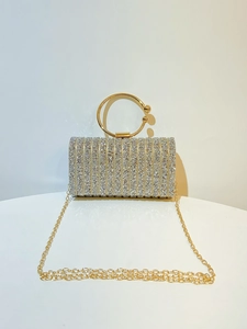 Detail of silver rhinestone evening bag with gold ring handle and metal chain