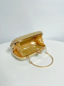Detail of evening bag showing champagne satin lining, pearl edges and large crystal ring clasp