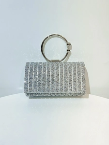 Detailed close-up of a silver clutch bag featuring vertical rhinestone patterns and a ring handle