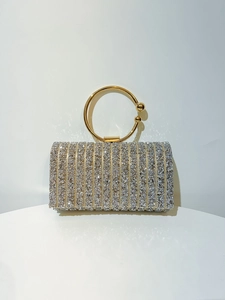 Macro view of silver rhinestone evening clutch with elegant gold circular metal handle