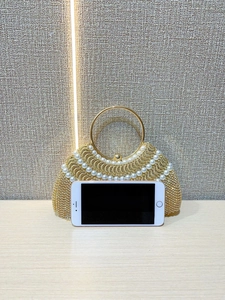 Détail du sac de soirée doré de luxe avec perles blanches et pompons en strass brillants