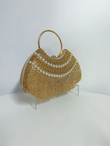 Détail macro d'un sac de soirée doré de luxe avec perles blanches et glands en strass
