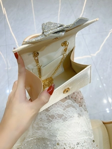 Champagne satin evening bag with crystal bow detail and detachable gold chain strap