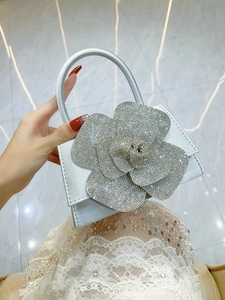 Detailed view of silver satin evening bag featuring a large sparkling rhinestone flower
