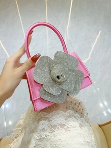 Detailed view of shimmering rhinestone flower decoration on pink satin evening handbag