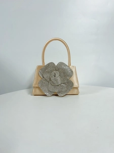 Detail of champagne gold satin evening bag with a large rhinestone floral embellishment