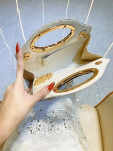 Sparkly evening clutch bag with golden circular handle and detachable chain strap