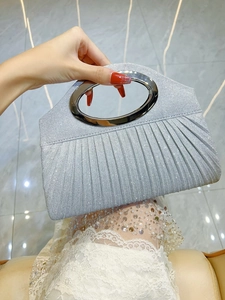 Detailed view of silver glitter clutch bag with pleated texture and metal handle